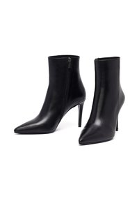 Bottines en cuir noir avec des bouts pointus, des zips sur les côtés et des talons aiguilles de 10 cm. Texture lisse et design épuré.