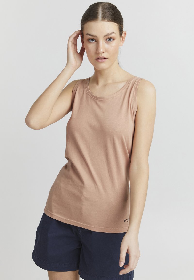 Lysebrun ermeløs tanktop i myk bomull, med rund hals og avslappet passform, kombinert med marineblå shorts.