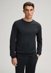 Zwarte sweatshirt met lange mouwen, een ronde hals en geribbelde manchetten en zoom. Bevat een subtiele logo op de borst. Zacht materiaal en casual pasvorm.