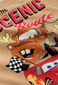 Rusty tow truck with big teeth and smiling red race car holding a checkered flag, with text "The Scenic Route."