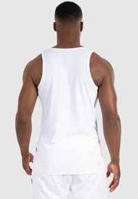Débardeur en coton blanc avec une coupe décontractée, présentant de larges bretelles et sans motifs visibles. Texture lisse, design simple.