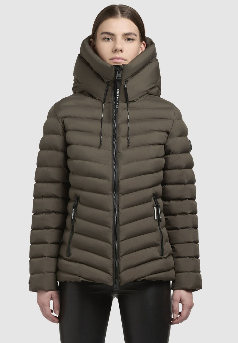 Olīvzaļa pūkainā jakā ir augsta apkakle, ar rāvējslēdzējs, un horizontālas šuves. Tā ir aprīkota ar rāvējslēdzēja kabatām un kapuci ar auklu.