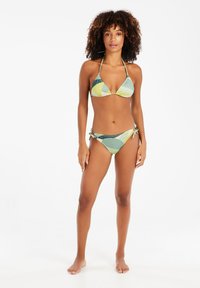 Bikini komplektas su trikampiu liemenėliu ir šoninėmis juostelėmis. Pagamintas iš daugiakampio rašto audinio, kuriame yra žalių, geltonų ir mėlynų atspalvių.