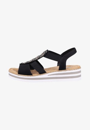 Sandale noire avec des brides élastiques, des accents décoratifs en argent, une semelle intérieure rembourrée et une semelle compensée rayée en blanc et gris.