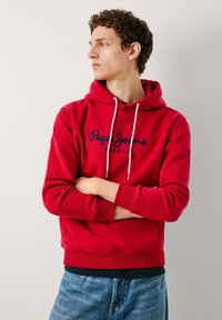 Rode sweatshirt met een trekkoordcapuchon, voorzien van een marineblauw logo "Pepe Jeans London" op de voorkant. Zachte stof en geribde manchetten.
