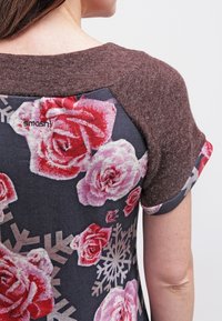 Top de manga corta con un estampado floral oscuro que presenta rosas en tonos rosa y rojo, un fondo gris y acentos de punto marrón en los hombros.