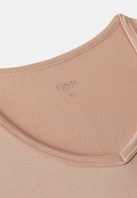 Light pink fabric t-shirt with a rounded neckline. Features a subtle texture and visible stitching. Brand name "FINN" printed inside the collar.