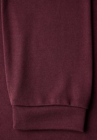 Burgundské košile s dlouhým rukávem jsou vyrobeny z látky s texturovaným, žebrovaným vzorem. Manžety mají přiléhavý design a prezentují měkký, elastický materiál.