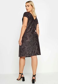 Lyhyet hihat, V-pääntie, tummilla paljeteilla varustettu mekko, jossa on pystysuuntaiset raidat, polvipituinen. Yhdistetty mustiin remmillisiin korkoihin.