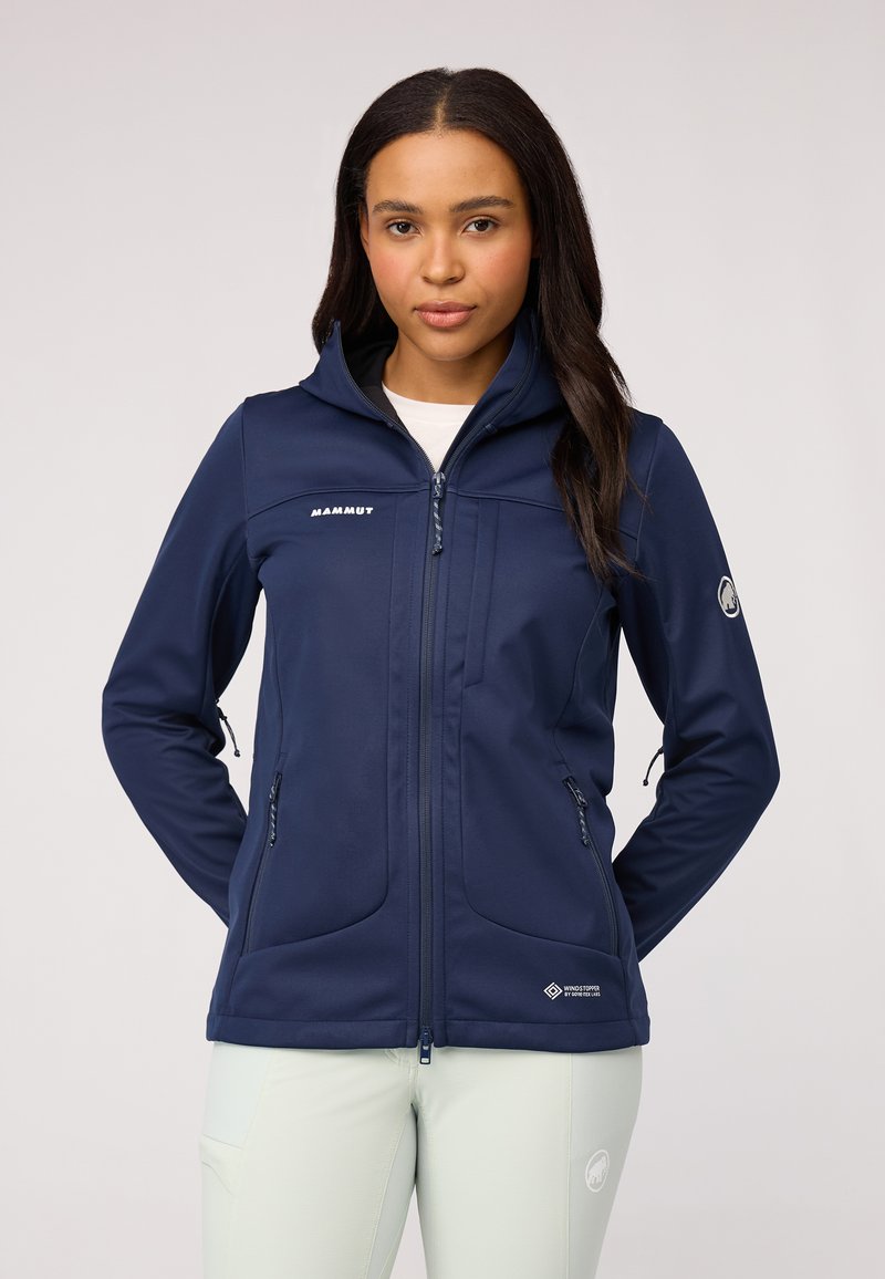 Tamsiai mėlynas softshell švarkas su užtrauktuku priekyje, dviem šoninėmis kišenėmis ir aukštu apykakle. Su logotipu ant krūtinės ir peties. Sklandus paviršius.