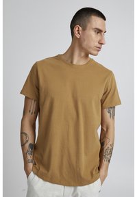 Brown cotton t-shirt with short sleeves, a crew neck design, and a relaxed fit. Features minimal seams and a smooth texture.