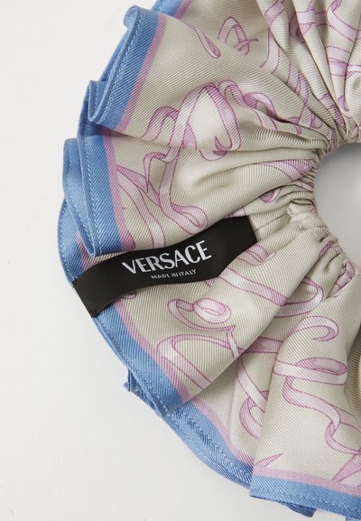 O bandă din mătase cu un design patterned în nuanțe de roz și albastru, având un eticheta Versace neagră care indică "Fabricat în Italia". Material moale, texturat.