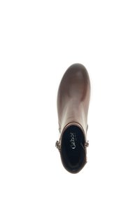 Bottine en cuir marron avec une texture lisse, bout arrondi et accent de boucle sur le côté. L'intérieur présente un revêtement noir avec le nom de la marque.