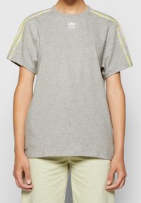 Grå bomullströja med korta ärmar, med flerfärgade ränder på axlarna och en vit Adidas-logotyp på bröstet.