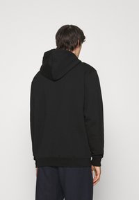 Černá mikina s kapucí, velká zadní kapsa, vroubkované manžety a spodní lem, vyrobená z měkké, strukturované látky, s kapucí na stahování.