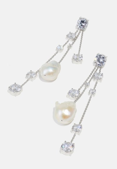 Μακριά ασημένια σκουλαρίκια που διαθέτουν δύο ακανόνιστους λευκούς μαργαρίτες και αρκετούς στρογγυλούς, διαφανείς κρυστάλλους σε συνδεδεμένες αλυσίδες με γυαλιστερή φινίρισμα.