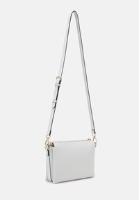 Světle šedá kožená crossbody taška s obdélníkovým tvarem, nastavitelným popruhem, zlatým kováním a černými detaily.