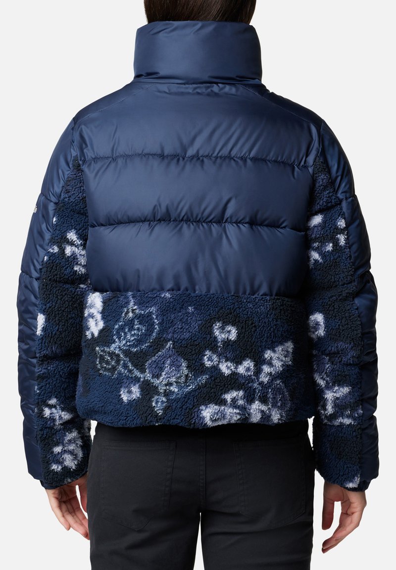Veste matelassée bleu marine avec un dos en sherpa texturé à motifs floraux, un col montant et une coupe courte. Durable et chaude.