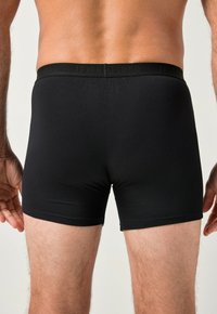 Czarne bokserki bawełniane z wąską gumką w pasie z nazwą marki "JP1880". Gładka faktura, dopasowany krój i długość do połowy uda.