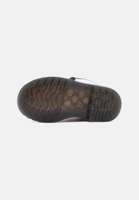 Σόλα μαύρου καουτσούκ παπουτσιού με υφή για καλύτερη πρόσφυση και ορατό τετράγωνο λογότυπο στο κέντρο, από κάτω σε λευκό φόντο.