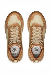 Hellbraune Sportschuhe mit einer strukturierten Oberseite und kontrastierenden beigen Akzenten, Schnürverschluss und rundem Logo auf der Innensohle.