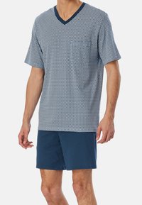 Navy and white geometric patterned short-sleeve V-neck shirt paired with solid navy shorts, featuring a relaxed fit and soft texture.