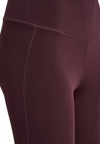 Burgundowe legginsy wykonane z elastycznego materiału. Gładka tekstura z płaskimi szwami po bokach dla wygody i trwałości. Wysoki stan.