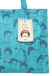 Sac bleu canard avec des illustrations de Frida Kahlo, doté d'un tissu texturé et d'une étiquette cousue détaillant la collaboration avec Frida Kahlo.