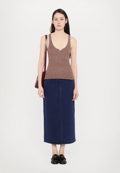 Top in maglia a righe marroni con bordi a scallop, abbinato a una lunga gonna in denim blu. Mocassini neri con dettagli in oro.