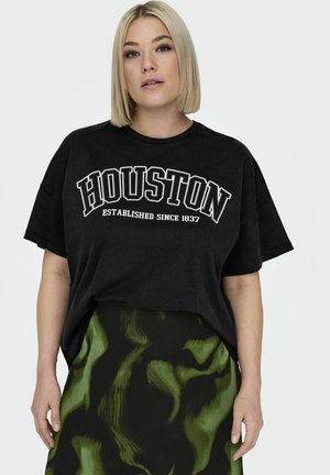 Camiseta negra de gran tamaño con el texto "HOUSTON" en blanco y "ESTABLECIDO DESDE 1837" debajo. Combinada con una falda de patrón verde y negro.