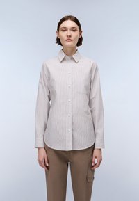 Long-sleeve button-up shirt in light gray with white vertical stripes, featuring a chest pocket and a classic collar. Smooth cotton fabric.