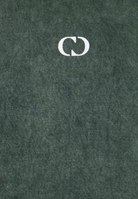 T-shirt en coton vert avec une texture douce, arborant un logo blanc imprimé sur le devant. Design simple, col rond, manches courtes.