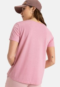 Camiseta de manga corta de color rosa claro con un corte holgado. Material suave, cuello redondo y detalles de costura sutiles.