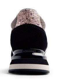 Zapatilla de ante negra con parte superior de malla, acentos brillantes en oro rosa y suela negra brillante. Presenta un talón acolchado y detalle del logo.