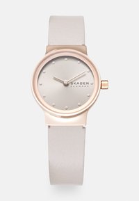 Pink gold-tone watch with a silver dial, minimalist dot markers, and a smooth white leather strap. Simple design with a sleek, modern look.