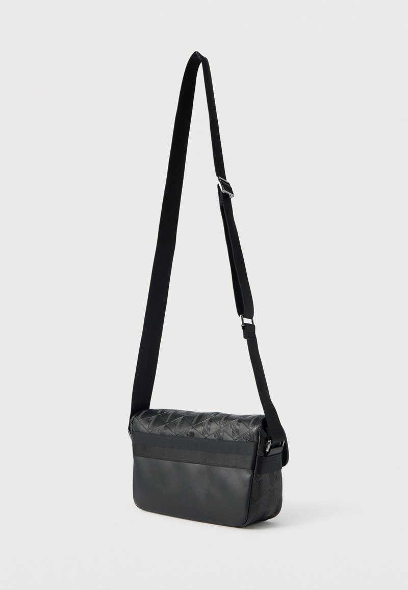 Sort crossbody-taske med en tekstureret, quiltet top og en glat nederste sektion. Har en justerbar rem og et slankt, minimalistisk design.