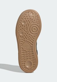 Suola di scarpa Adidas in materiale gommoso beige. Presenta un motivo testurizzato che include cerchi e forme geometriche. Logo del marchio visibile.