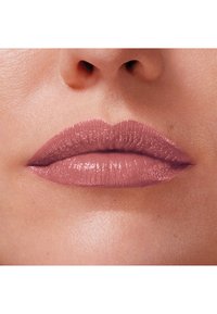 Rouge à lèvres dans une teinte mauve douce, présentant une texture brillante et une finition lisse, appliqué uniformément sur des lèvres bien définies.