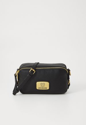 Borsa a tracolla in pelle nera con placca del logo dorata, chiusura con zip e tracolla regolabile. Presenta una superficie liscia e dettagli metallici.