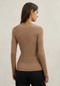 Top a maniche lunghe a coste in marrone chiaro, con scollo rotondo e silhouette aderente, realizzato in tessuto morbido ed elastico.