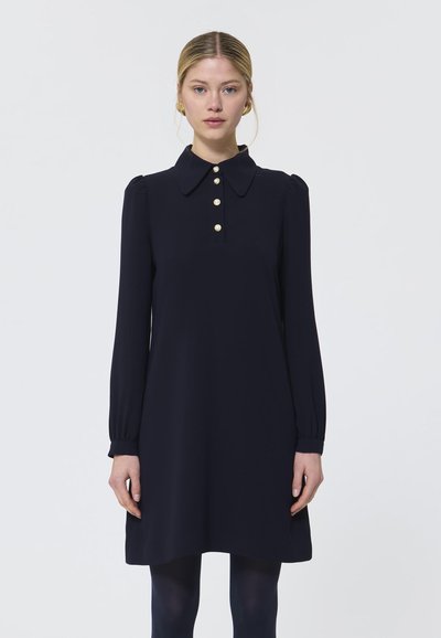 Abito blu navy con colletto, maniche lunghe e dettagli con bottoni dorati. Tessuto morbido e liscio con una forma svasata e accenti arricciati sulle maniche.