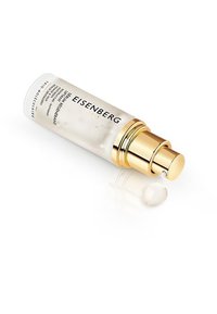 Eisenberg-Serum in einer transparenten, satinierten Glasflasche mit goldenem Pumpendeckel; daneben befindet sich eine kleine Menge cremig-weißer Produkt.