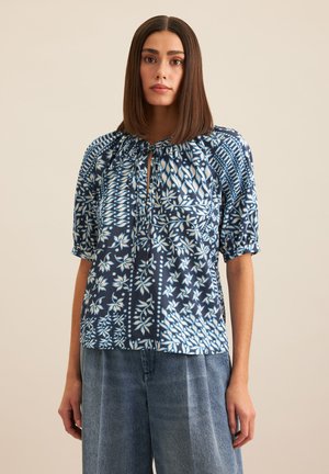 Navy blue patterned blouse with short puff sleeves, features a lace-up neckline, and intricate white floral designs throughout.