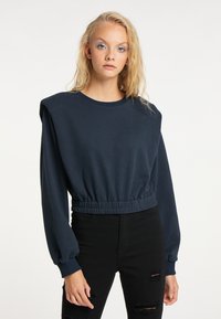Felpa cropped blu navy con maniche lunghe a sbuffo e un orlo arricciato elastico. Presenta un classico collo a girocollo e una texture liscia.