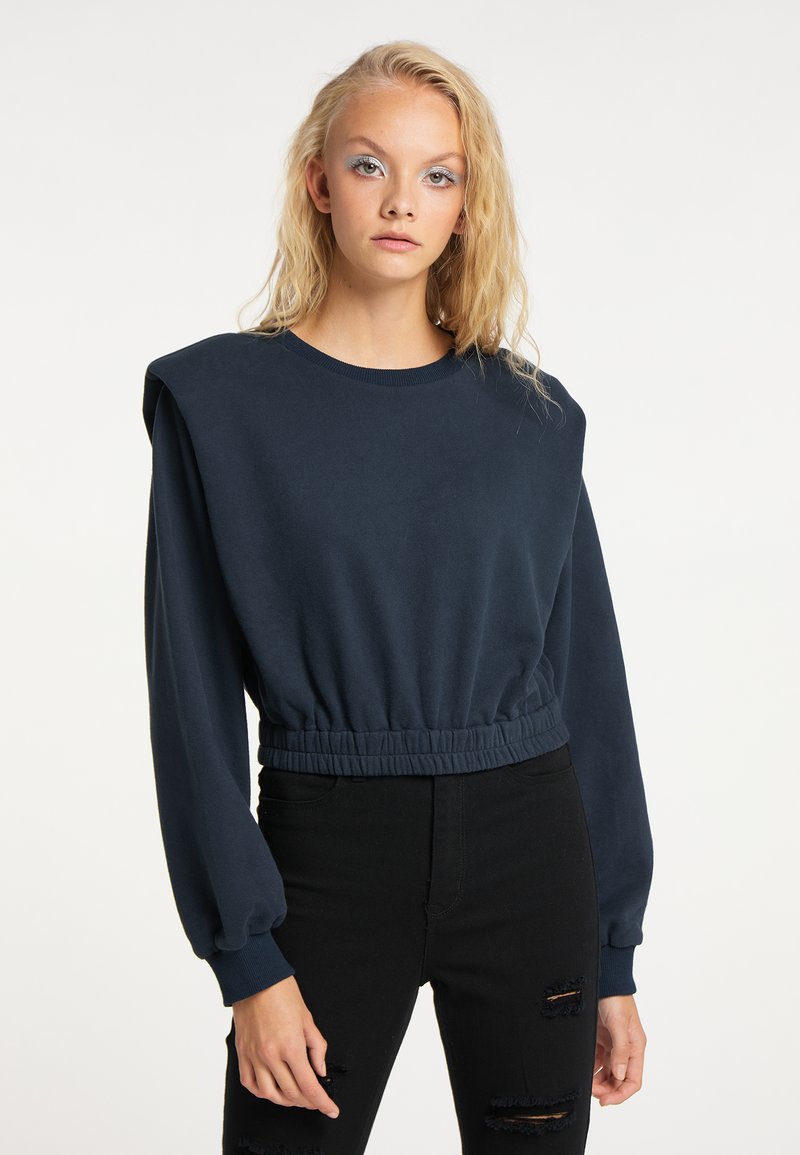 Felpa cropped blu navy con maniche lunghe a sbuffo e un orlo arricciato elastico. Presenta un classico collo a girocollo e una texture liscia.