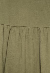 Tessuto verde oliva con una trama texture. Presenta un design arricciato alla base, creando morbidi plissè per un maggiore volume.