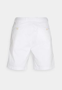 Shorts en coton blanc présentant un design classique, avec une face avant plate, des poches arrière ornées de boutons jaunes, et une coupe décontractée.