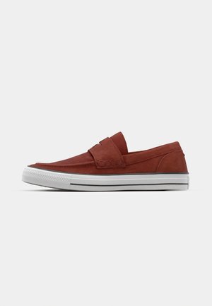 Zapatos slip-on de gamuza en rojo óxido con parte superior texturizada, suela de goma blanca y sutiles detalles de costura. Diseño de punta redondeada.