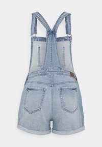 Ruoha sinivärisistä farkkareleissä, joissa on säädettävät hihnat, takataskut ja käänteet lahkeiden avauksissa. Silkkinen rakenne ja klassinen muotoilu.