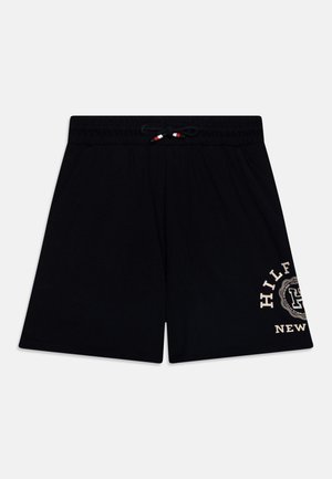 Pantalones cortos de algodón negros con una cinturilla elástica y cordón. Presenta un logo en color crema impreso en el lado izquierdo. Diseño simple, corte recto.